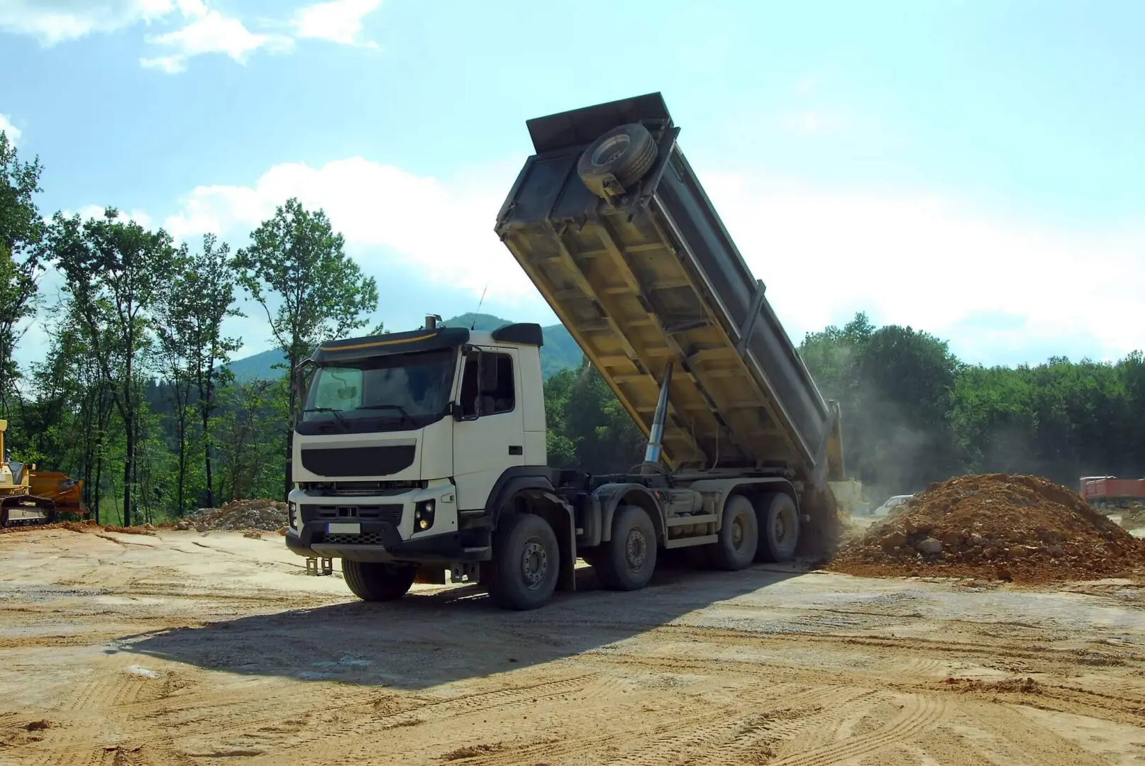 Dump truck unloading soil at a construction site.