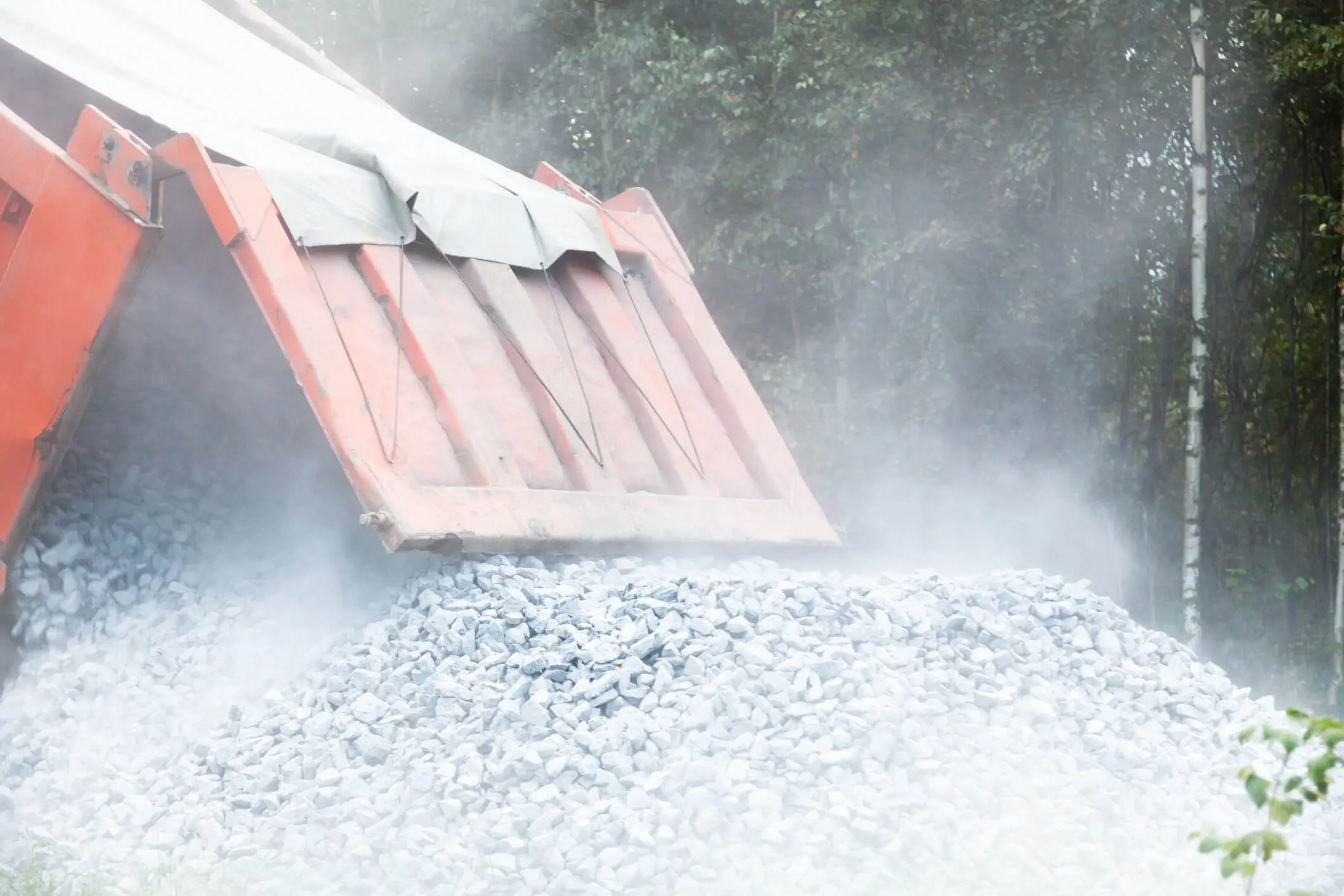 Dump truck unloading gravel onto the ground.
