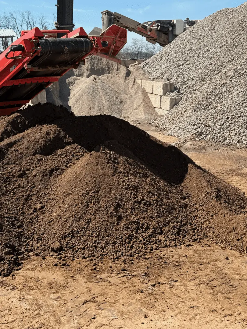 Piles of different construction materials including dirt and gravel at a site.