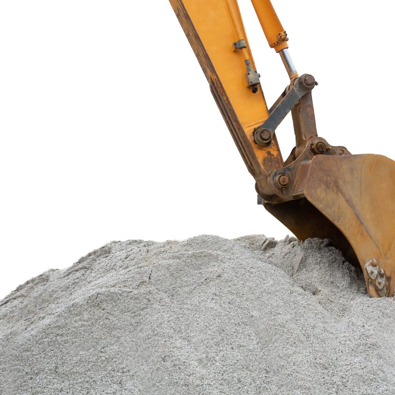 Excavator bucket scooping a pile of gravel or sand.